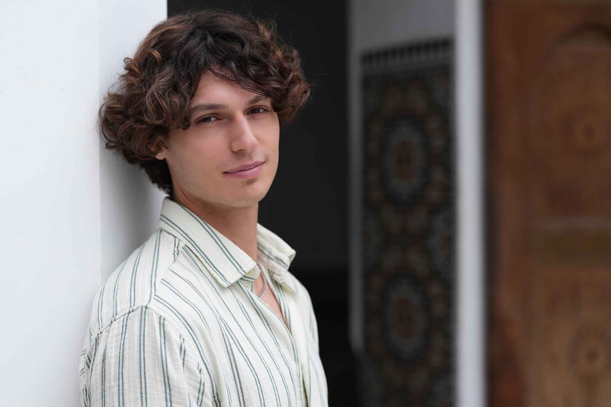 Sample image of a man leaning against a wall with the deep background bokeh Creative Look: Standard Click to open modal