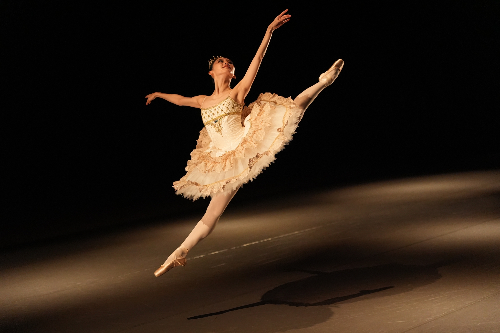 An image capturing the moment a ballerina is leaping high on stage Click to open modal