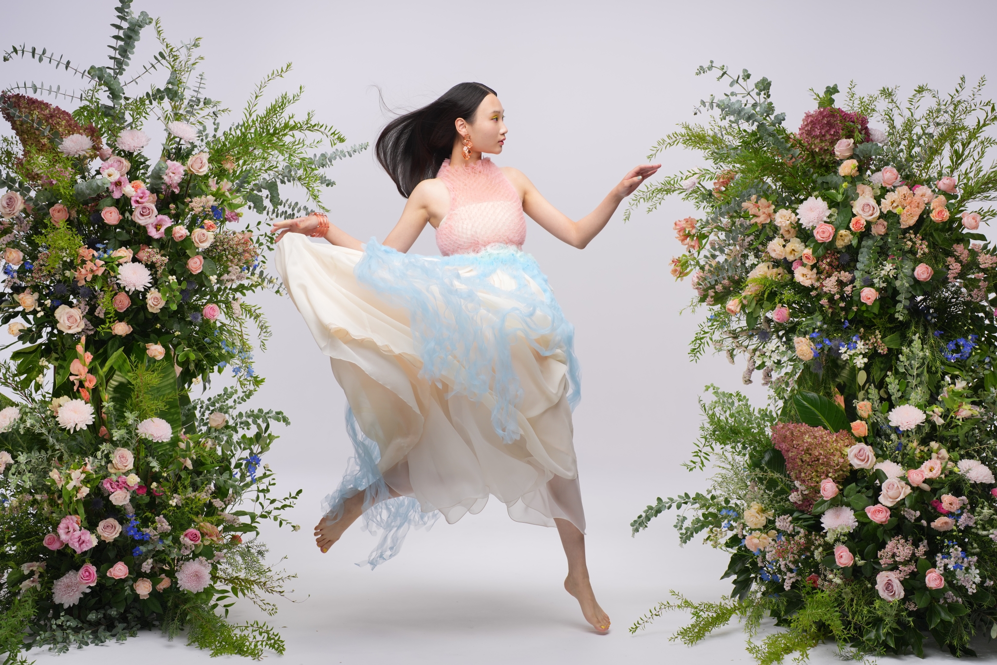 Example image showing a woman jumping between the floral arrangements in a photo studio  Click to open modal