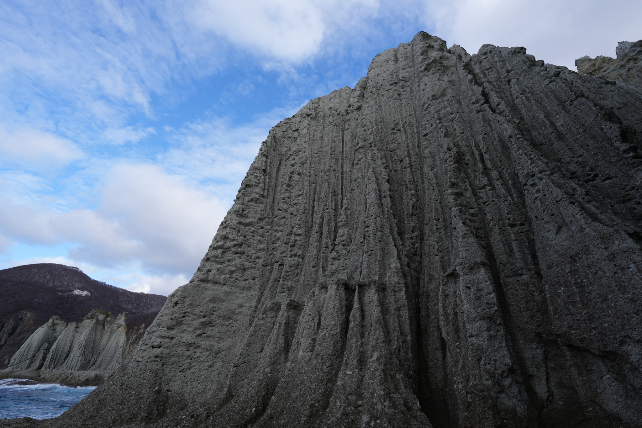 A wide photograph dynamically capturing a beautiful white rock cliff from the sea below. Click to open modal